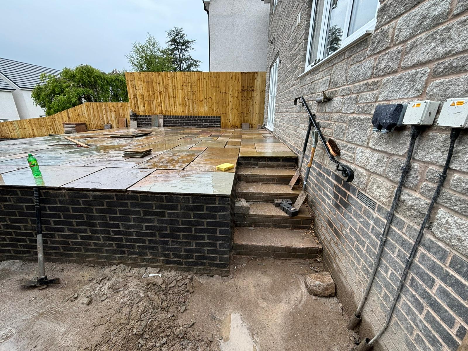 Raised Indian sandstone patio with brick retaining wall and steps by RD Construction, Aberdare